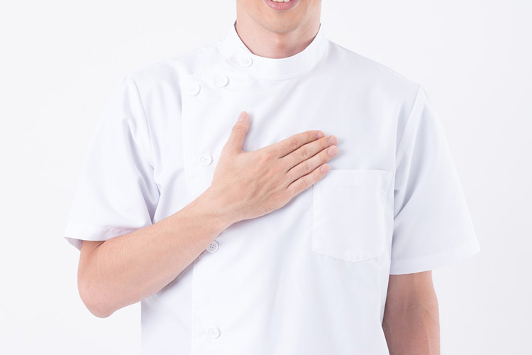 胸に手をあてる白衣姿の男性
